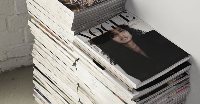 Smart Investments - High angle many fashion magazines stacked on floor against white brick wall in studio