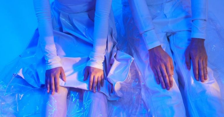 Automation Insights - Man and Woman in Futuristic Outfits Sitting on the Floor in Blue Lighting